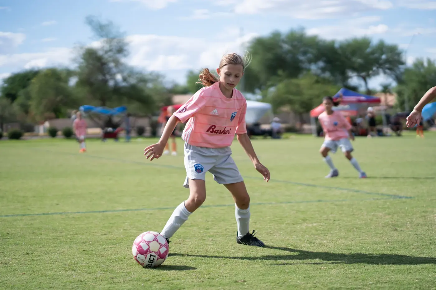 Chelsea in her pink jersey controls the ball during a daytime soccer game in 2022.