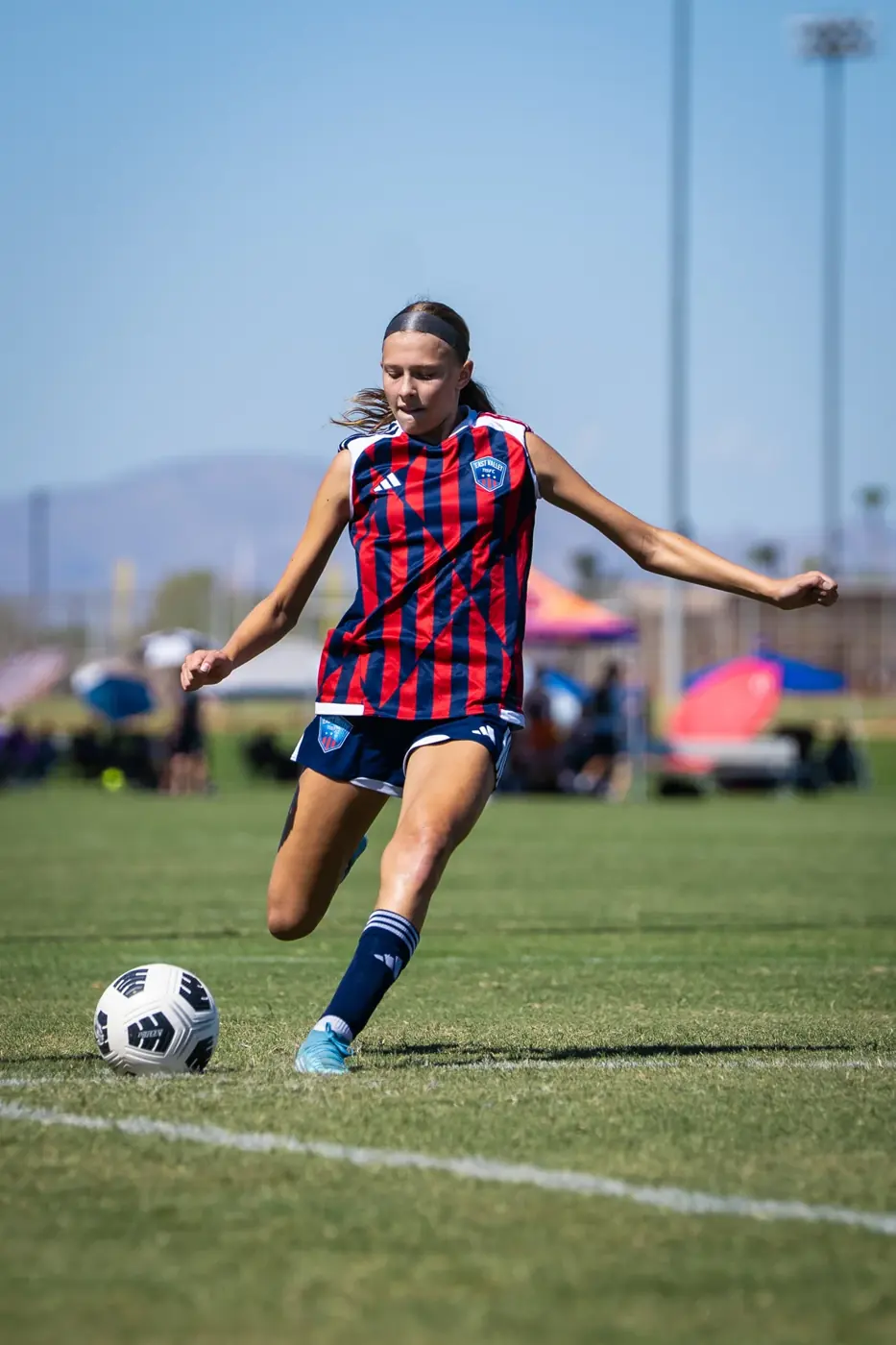 Chelsea in her red-and-blue jersey prepares to strike the ball in 2026.