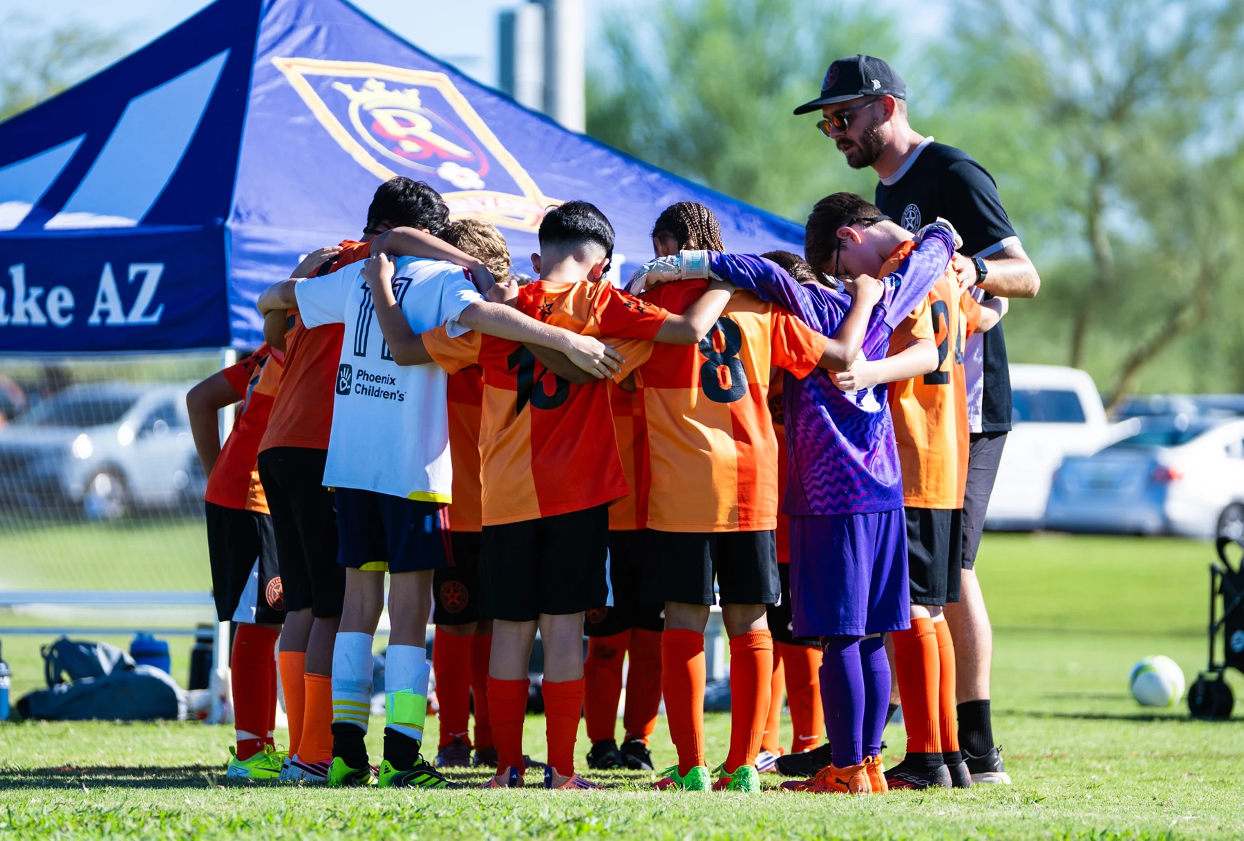 Players and their coach gather in a close team huddle before the game.