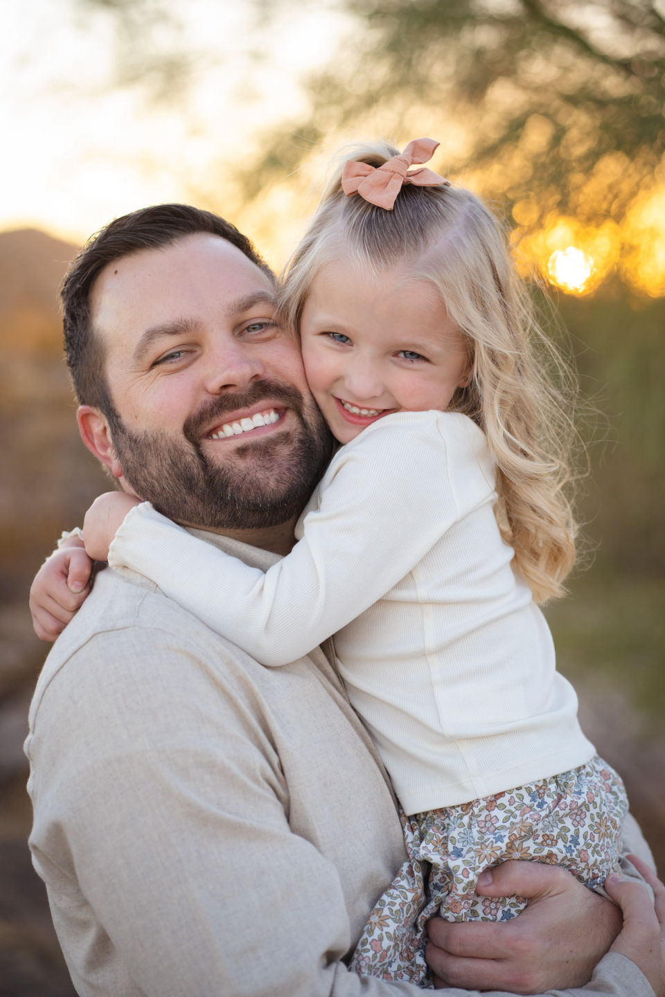 Smiling father holds his daughter close in golden evening light.