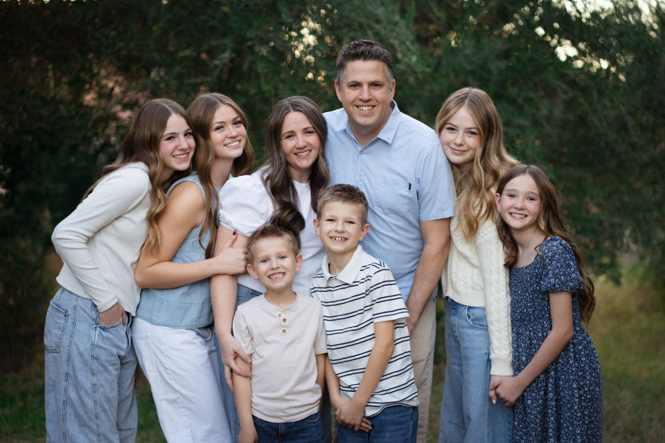 Family stands together along a tree-lined path.