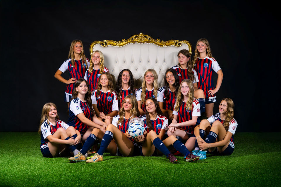 Smiling soccer teammates gathered around a white and gold throne.