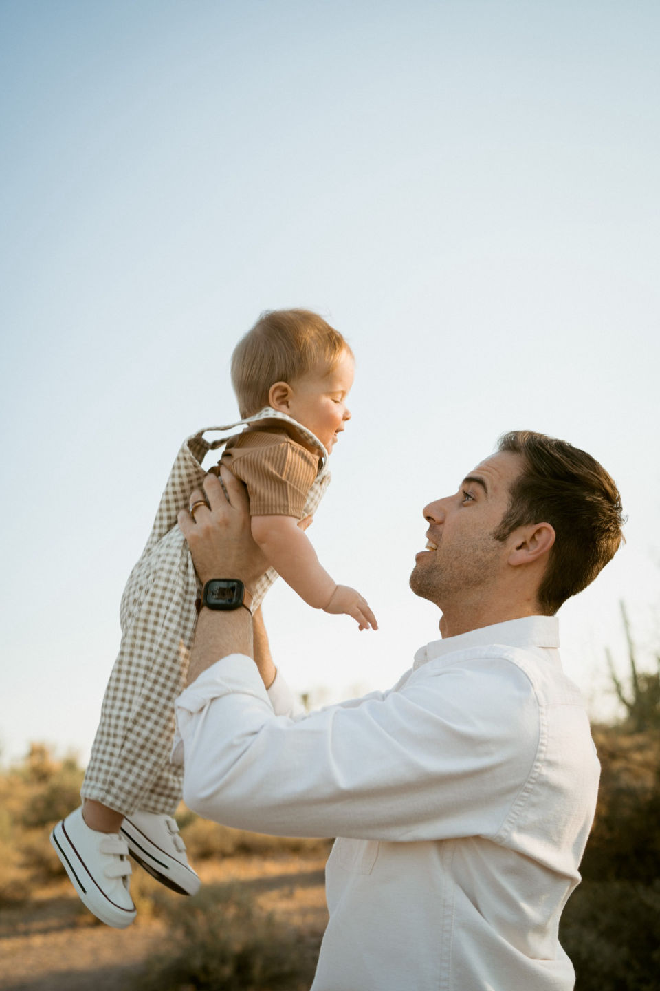 Father lifts his smiling child into the air.