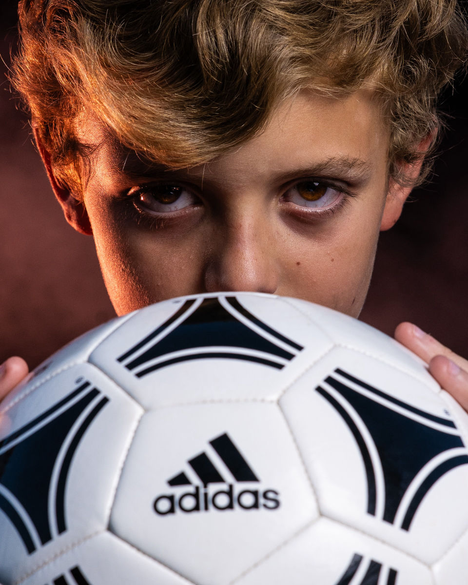 Close portrait of a soccer player looking over a black and white ball.