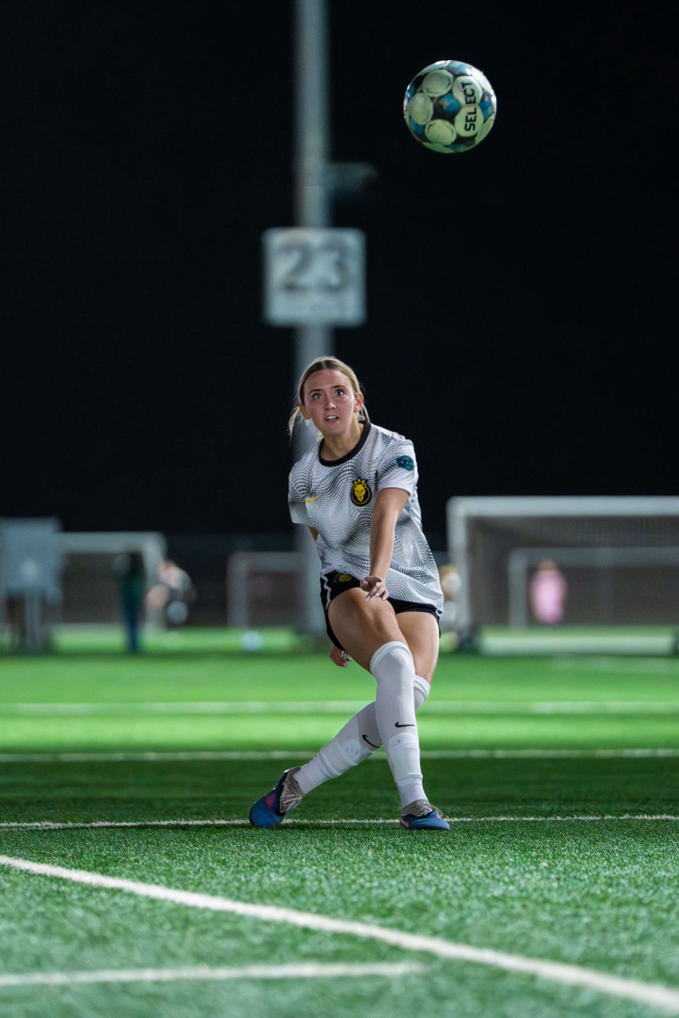Soccer player watches an airborne ball while preparing to receive it.