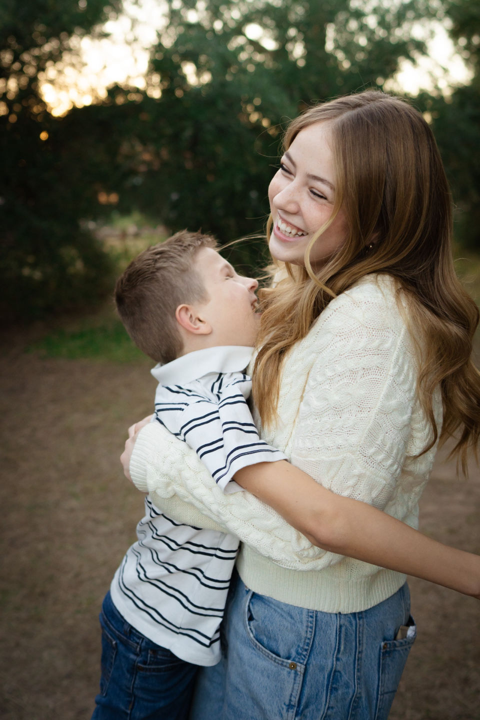 Older sister hugs her little brother in evening light.