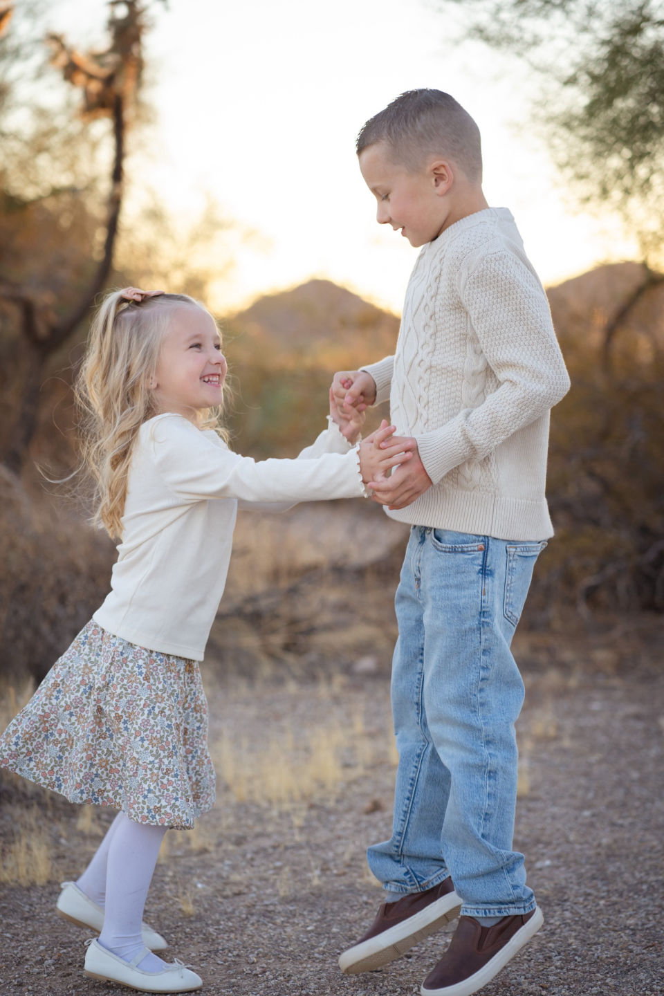 Two siblings hold hands together in the desert.