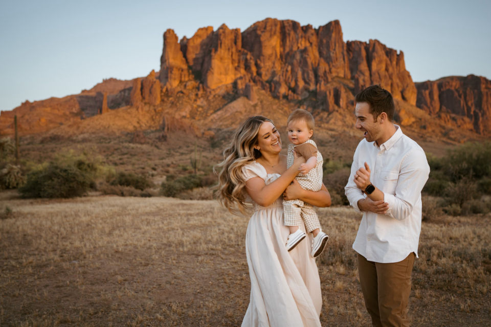 Parents laughing with their child beneath the mountains.