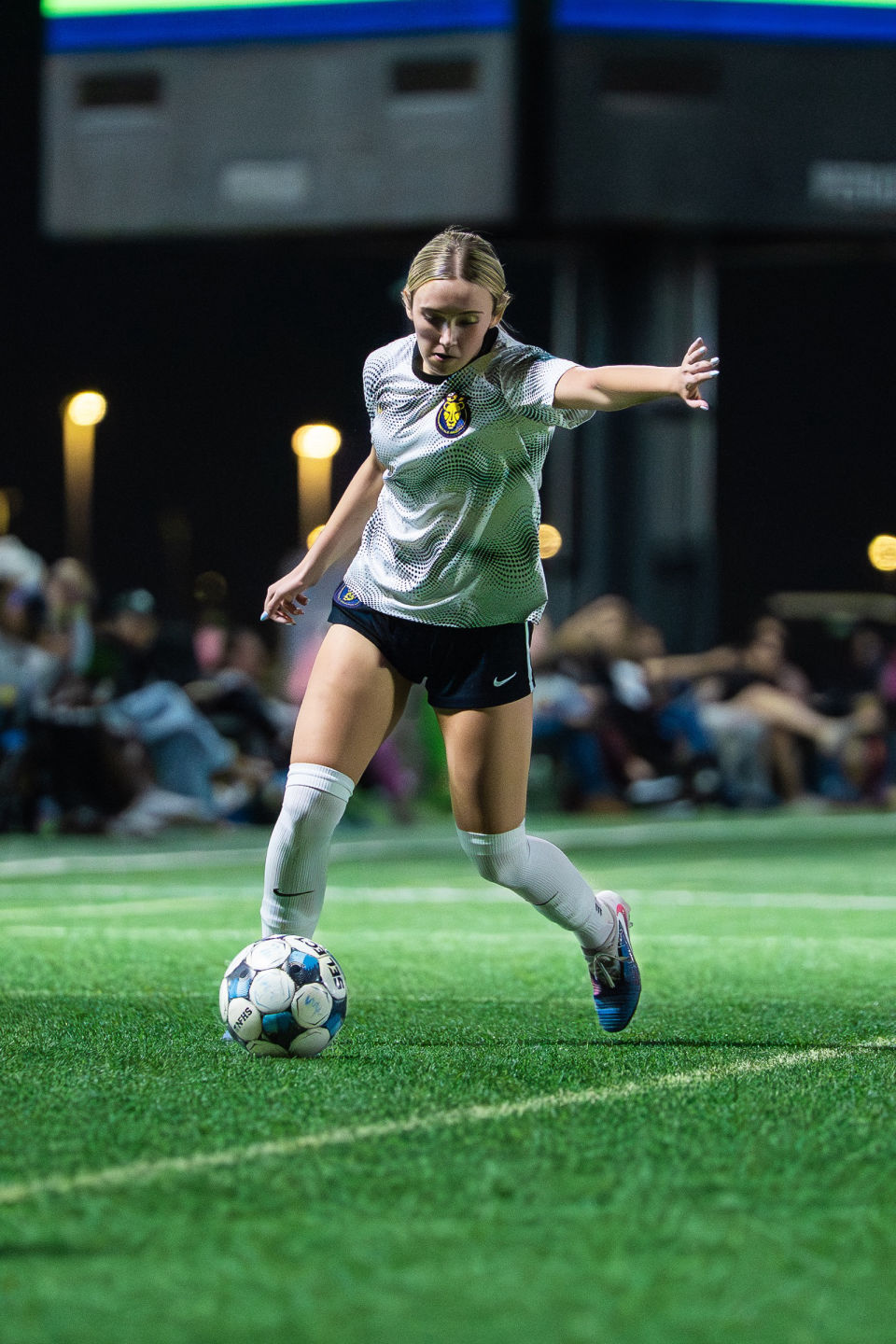 Soccer player in gray extends an arm for balance while controlling the ball.