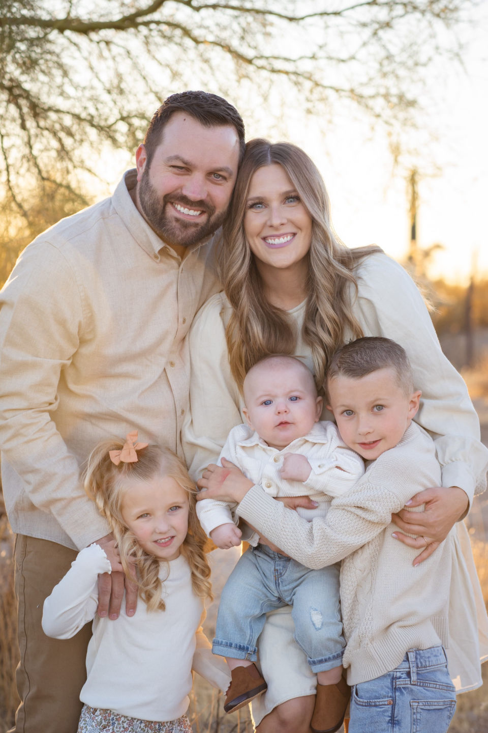 Parents and three children share a close family portrait outdoors.