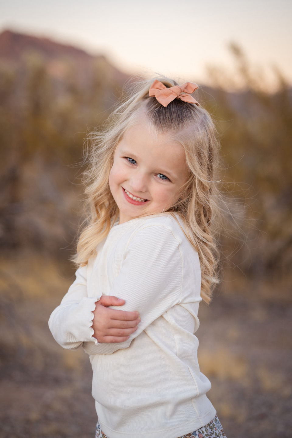 Young girl smiles over her shoulder in the desert.