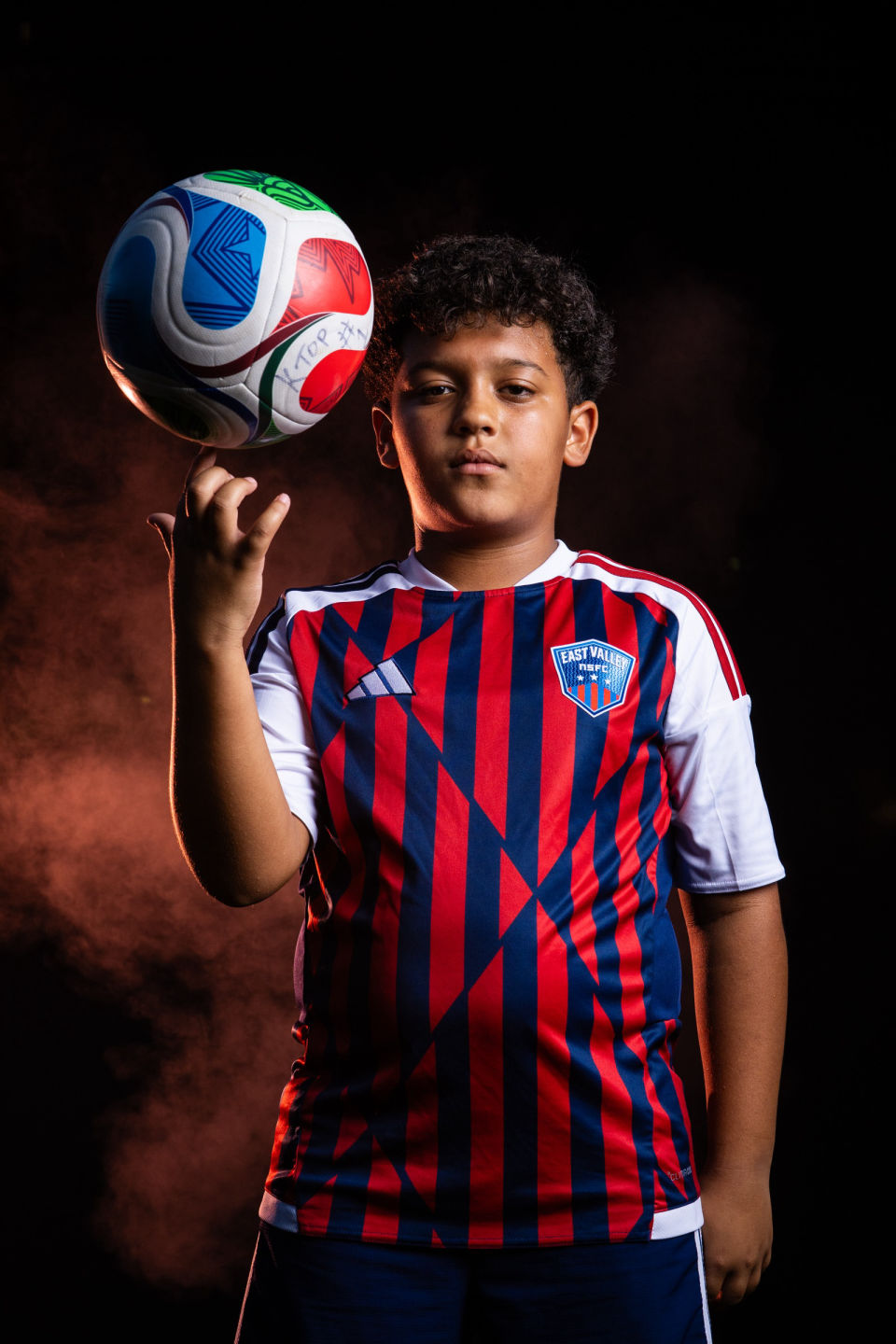 Soccer player balances a colorful ball on one finger.